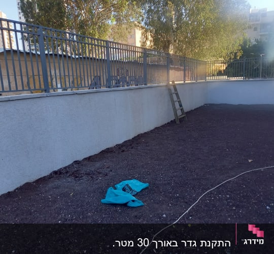 גדר מתכת עם סולם על קיר בטון